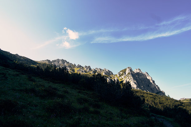 白天，开阔的田野上，拥有岩石山峰的山地景观在晴朗的蓝天下图片下载