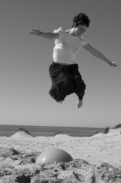 在沙滩上玩耍，跳跃被埋在沙子里的橡胶球，这是一段充满乐趣和欢笑的时光，伴随着休息时刻，照片为黑白。图片下载