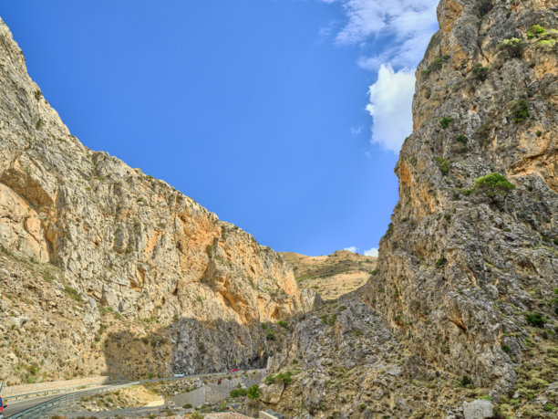 希腊克里特岛风光：蓝天白云下的崎岖山坡，岩石旱地，是旅行、自然和探险的理想素材图片下载