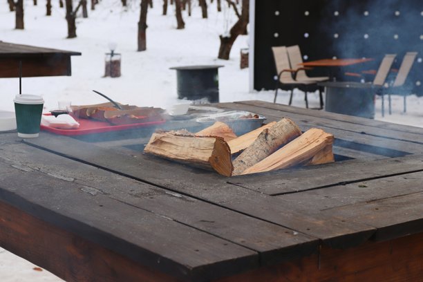 户外木桌上摆放着火盆和食物，营造冬日生活方式和温馨品牌形象图片下载