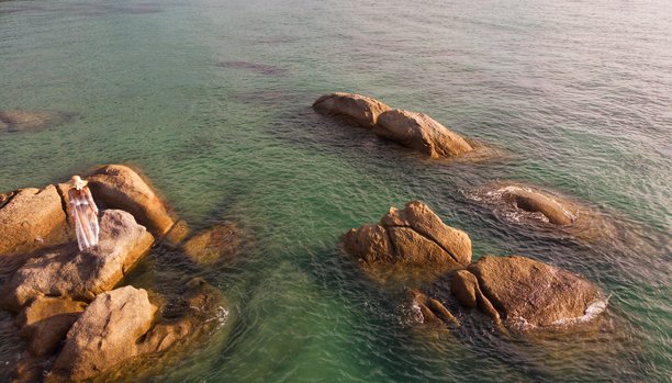 泰国苏梅岛热带岩石海岸，戴着面纱和遮阳帽的年轻女孩摆姿势，航拍照片图片下载