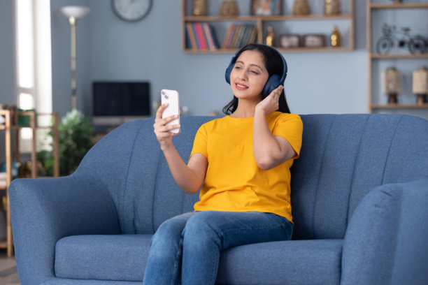 穿着黄色T恤的可爱小女孩在家中沙发上听音乐的特写照片图片下载