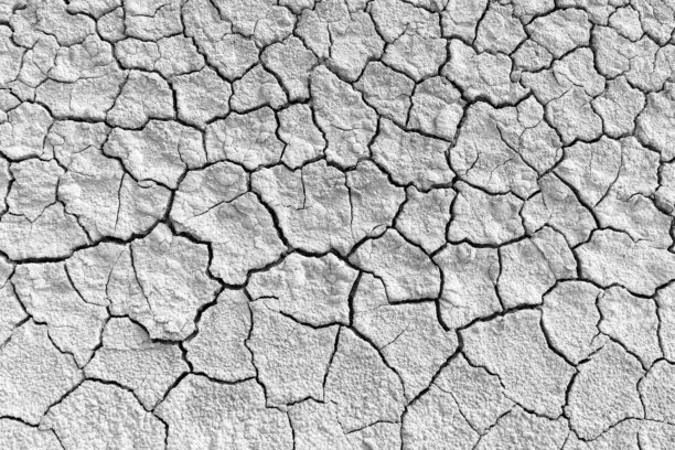 干裂的黑色和白色大地纹理，高对比度的黑白照片，描绘了贫瘠土地上干裂的泥土。深邃裂缝的复杂网络突显了严重的干旱条件和环境压力。图片下载