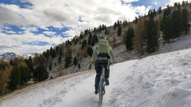 第一人称视角，跟随一名年轻男子骑行在雪地小径上的电动山地自行车图片下载
