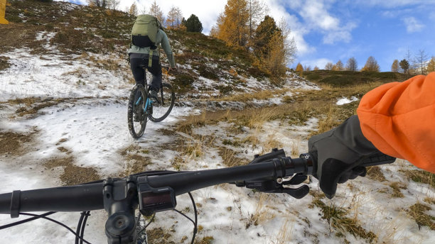 第一人称视角，跟随年轻男子在雪地小径上骑行电动山地自行车图片下载