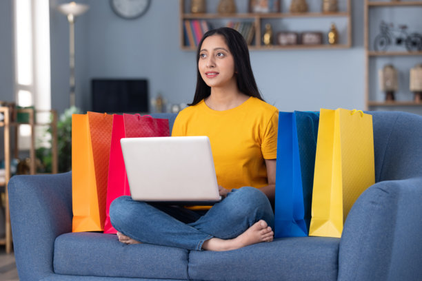 漂亮的年轻女孩在家里的沙发上用笔记本电脑进行在线购物的图片图片下载