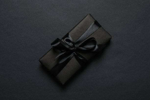 黑色星期五。黑色礼品盒俯视，系着丝带，置于深色背景上，为您提供宣传或推广空间图片下载