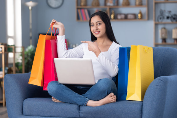 漂亮年轻女孩在家坐在沙发上用笔记本电脑网上购物的照片图片下载