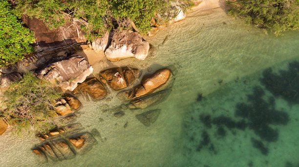 身着面纱和太阳帽的年轻女孩在泰国苏梅岛的热带岩石海岸摆姿势，航拍照片图片下载