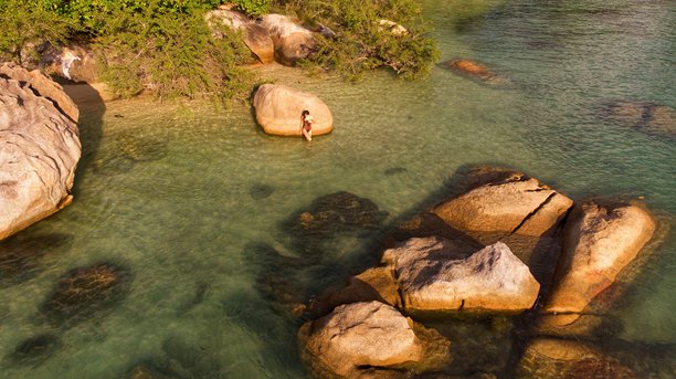 身着面纱和太阳帽的年轻女孩在泰国苏梅岛的热带岩石海岸摆姿势，航拍照片图片下载