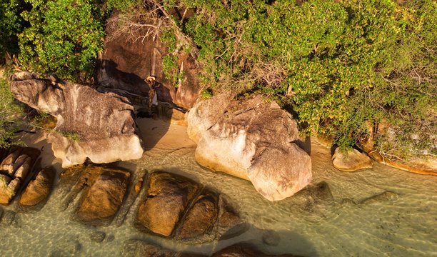 泰国苏梅岛热带岩石海岸边，戴着面纱和遮阳帽的年轻女孩摆姿势，航拍照片图片下载