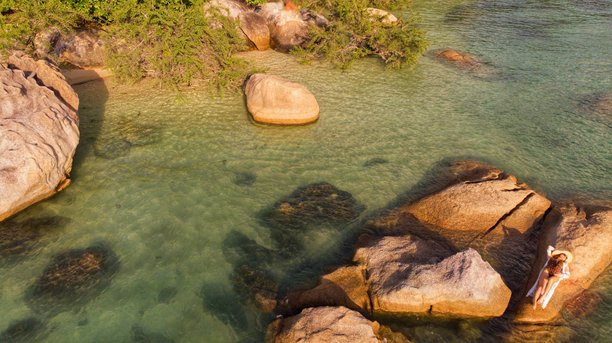 泰国苏梅岛热带岩石海岸边，戴着面纱和太阳帽的年轻女孩摆姿势，航拍照片图片下载