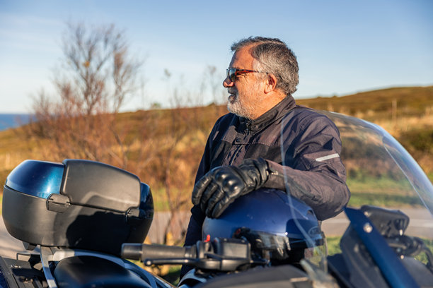 老年摩托车骑手在摩托车旅行途中于户外休息图片下载