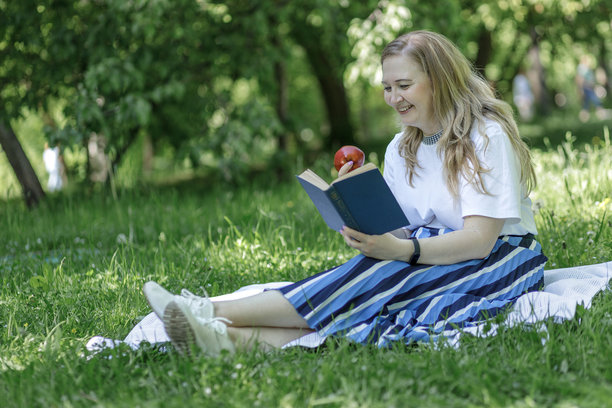 一位中年金发女子在花园的躺椅上使用笔记本电脑工作，绿色居家办公概念。图片下载