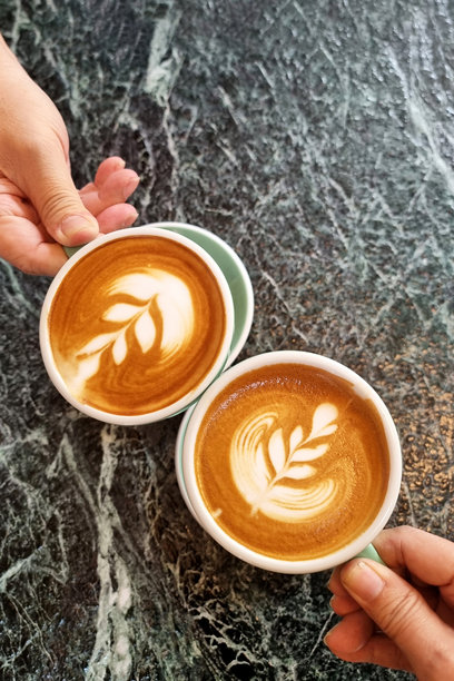 两个人举杯庆祝，咖啡上有着简单的郁金香拉花热拿铁。图片下载