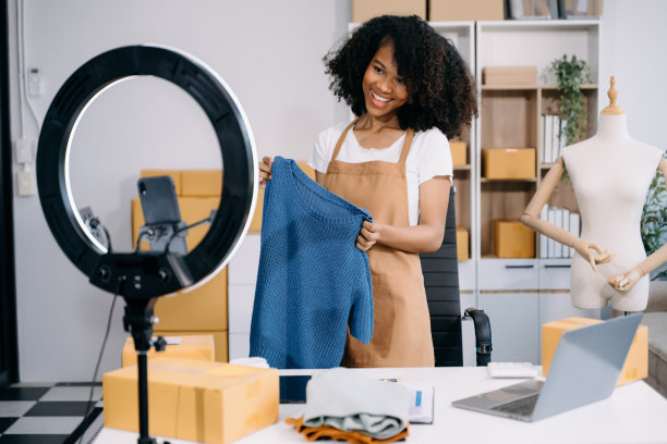 时尚博主概念，年轻女性通过视频直播卖衣服。创业小企业中小企业，使用智能手机图片下载