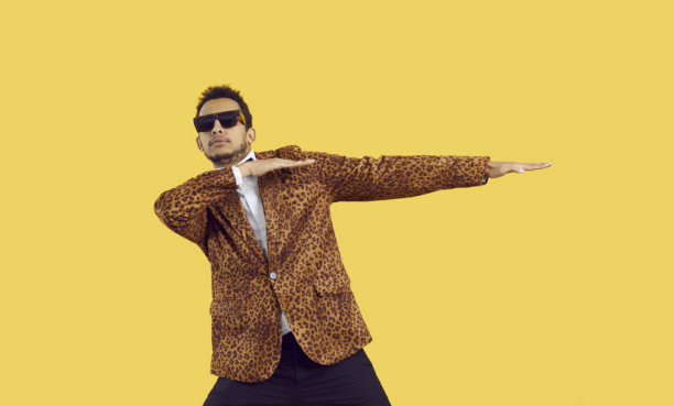 穿着豹纹夹克、戴着酷炫眼镜的搞笑黑人男子，在黄色背景上孤立地跳舞图片下载