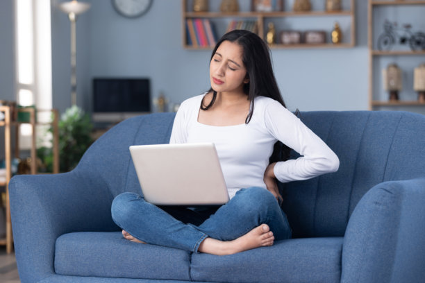 身穿时尚服装的年轻漂亮女孩在家中沙发上使用笔记本电脑的居家照片图片下载