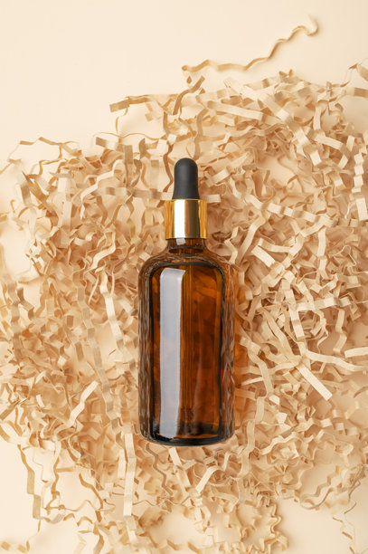 化妆品样机。琥珀棕色玻璃滴管瓶，置于米色背景的牛皮纸上。美容面部护理概念俯视。天然化妆品包装设计，精华，精油图片下载