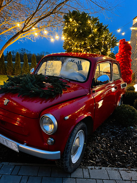 装饰着圣诞花环和彩灯的红色复古扎波罗热日斯塔 965 汽车，在节日夜晚的场景中图片下载