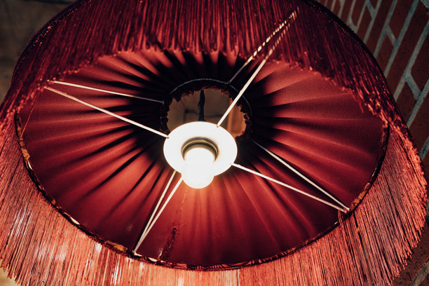 红色流苏灯罩和灯泡照亮了温暖的复古室内空间图片下载