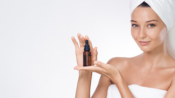 水疗护肤概念，展示琥珀色精华滴管瓶的女性图片下载