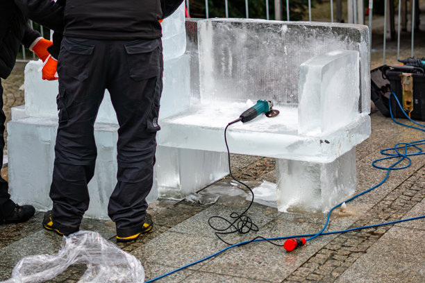 使用电动工具在城市空间雕刻冰凳，展示了创作临时冬季装置的过程图片下载