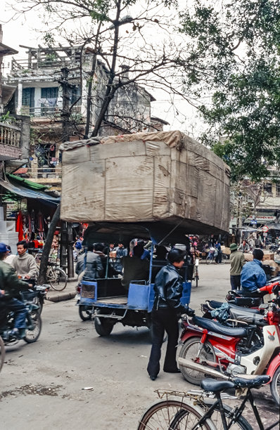 越南河内“36条街”的街道景象彩色历史照片，一辆三轮摩托车超载严重，拍摄于1995年3月5日图片下载