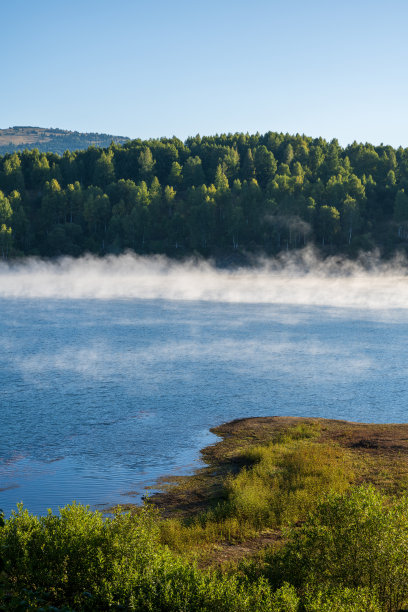一幅具有前景、中景和背景三个层次的自然照片。美丽的湖水，早晨的薄雾在其上空升腾。图片下载
