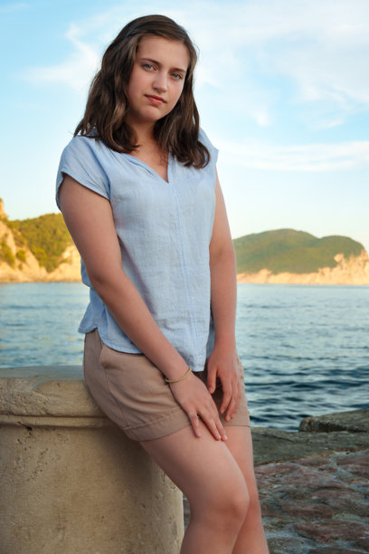 黑山佩特罗瓦茨，一位年轻女子倚靠着石头拍摄的肖像照。中景，略带微笑，夏日假期，地中海度假胜地，山地景观。图片下载