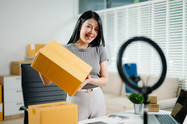 时尚博主概念，年轻亚裔女性通过视频直播售卖衣物。创业小企业，使用智能手机或平板电脑接收订单图片下载