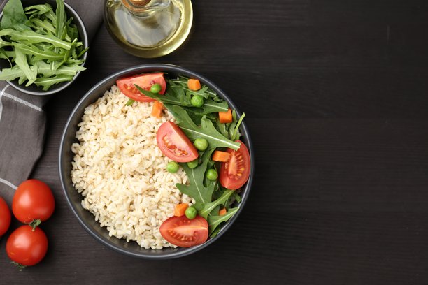 美味的糙米饭搭配蔬菜，摆放在黑色木桌上，俯视角度。留有文字空间。图片下载