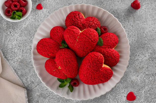 心形泡芙配红色闪电脆皮和覆盆子奶油——情人节甜点，摆放在盘子里，背景为混凝土。俯视角度，留有复制空间。图片下载