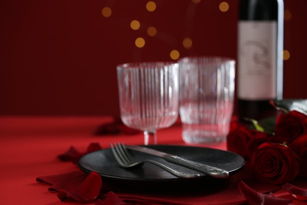 浪漫晚餐的餐桌摆设，配有玫瑰花，拍摄于红色桌面上，特写镜头，留有文字空间图片下载