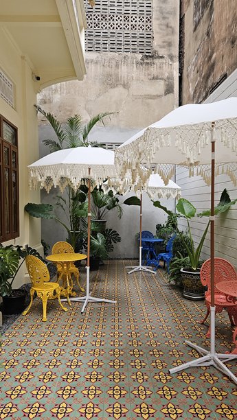 泰国曼谷 - 2025年9月20日 - 户外咖啡馆露台，配有色彩鲜艳的椅子、图案瓷砖和装饰伞的照片图片下载