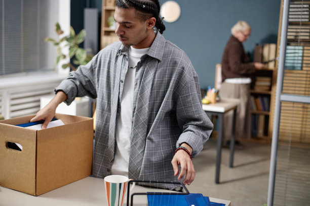年轻的黑人成年人在现代办公空间打包办公用品图片下载