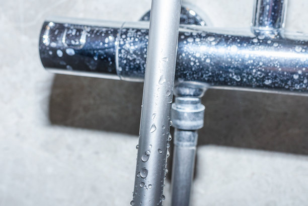 石灰水，卫生概念。水滴在淋浴管上，覆盖着水垢的恒温淋浴龙头。特写。图片下载