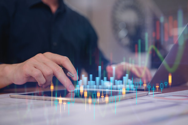 商人在家庭办公室使用电脑和数字平板工作，屏幕上显示虚拟投资股票数据图表，概念涉及投资金融商业营销和计划图片下载