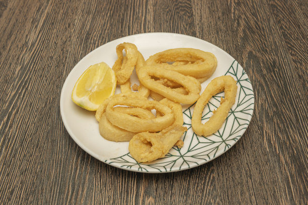 一张捕捉到精确烹炸瞬间的照片，展示了鱿鱼圈是如何获得均匀且完美的金黄色的图片下载