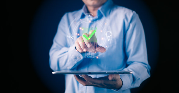 一个人正在使用平板电脑，屏幕上显示一个发光的绿色勾号图标，旁边是数字文件以及代表流程批准、数字工作流、文件验证、效率和在线授权的符号。图片下载