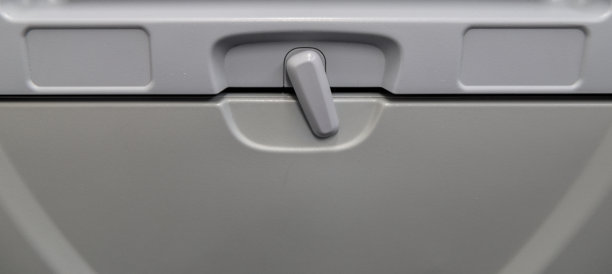 飞机经济舱座位下收起的餐桌托盘，下方是娱乐屏幕和电源插座（已关闭），特写，飞行中的餐食选择，航空旅行，休闲，商务，头等舱图片下载