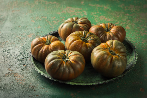 绿色复古背景上的黑色大番茄图片下载