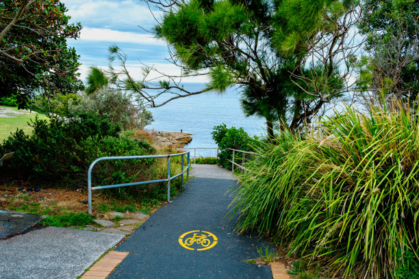 这张照片摄于2025年12月，位于悬崖步道上的Hungry Point Reserve，展示了望向Bundeena和Maianbar的海岸线景色，人们正在享受徒步和海岸生活。图片下载