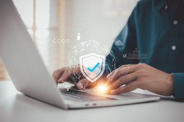数字安全与全球网络防护：男子使用带有盾牌图标的笔记本电脑，象征网络安全和数据隐私图片下载