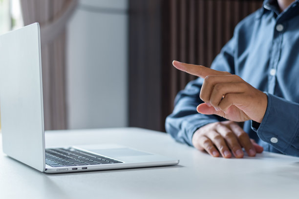 商务人士在现代办公室工作时，用手指着笔记本电脑屏幕图片下载