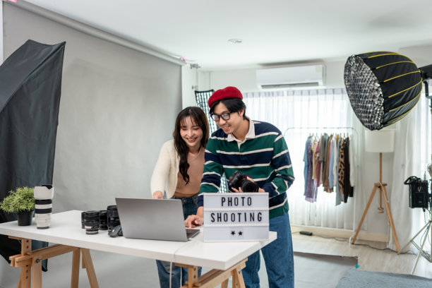 亚洲美女模特与摄影师在摄影棚工作。一位有吸引力的专业摄影师用背景布为年轻女孩拍摄精美照片，为广告创作影像。图片下载