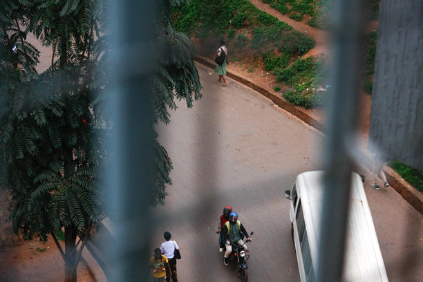 从高处俯瞰基加利一片葱郁小径旁的行人与骑摩托车的人图片下载