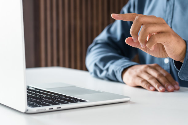 商务人士在现代办公室工作，手指指向笔记本电脑屏幕图片下载