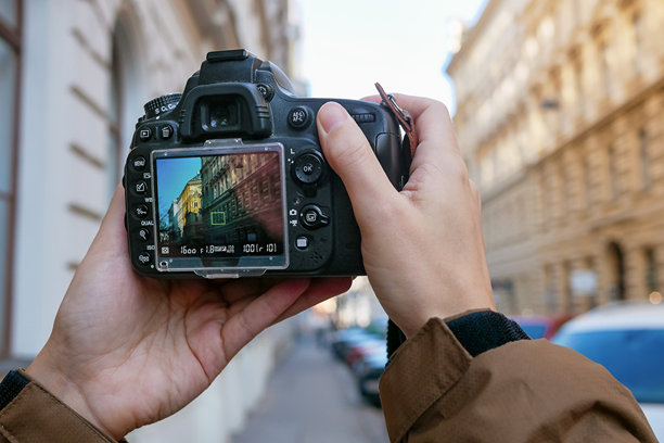 摄影师在城市街道上用单反相机拍摄城市建筑照片图片下载