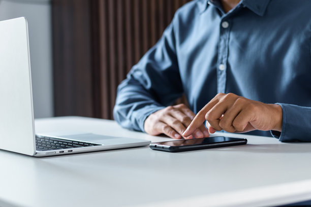 商务人士在办公室的桌子旁使用手机应用程序触摸智能手机屏幕图片下载